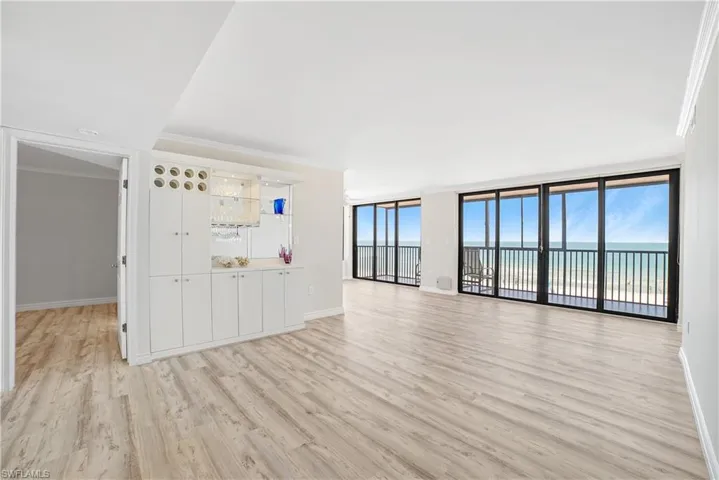 Unfurnished living room with light wood-type flooring, a wealth of natural light, a water view, and crown molding