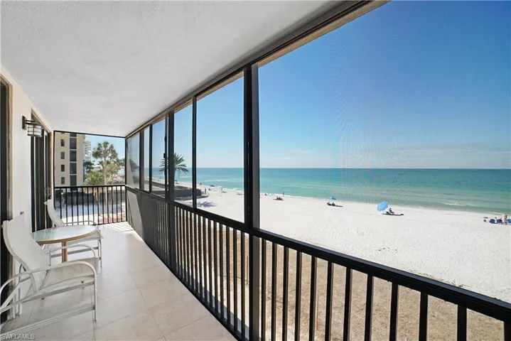 Sunroom / solarium featuring a beach view and a water view