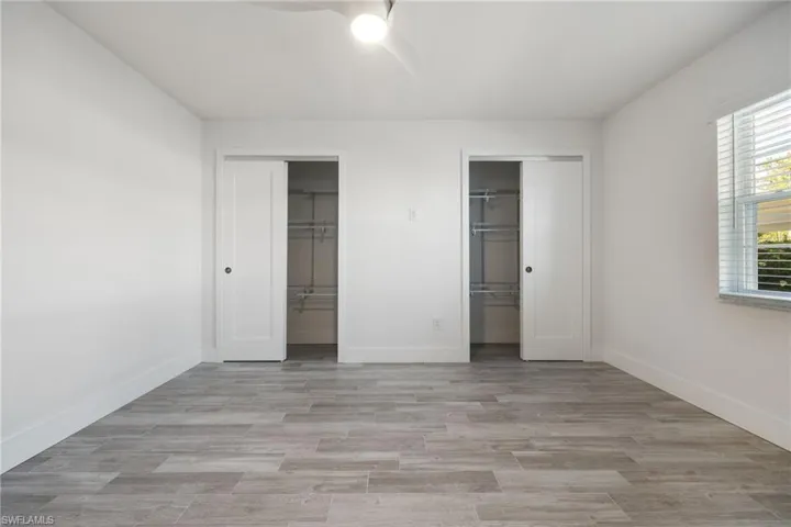 Spacious room featuring light gray wood-finish flooring, white walls, and a ceiling fan