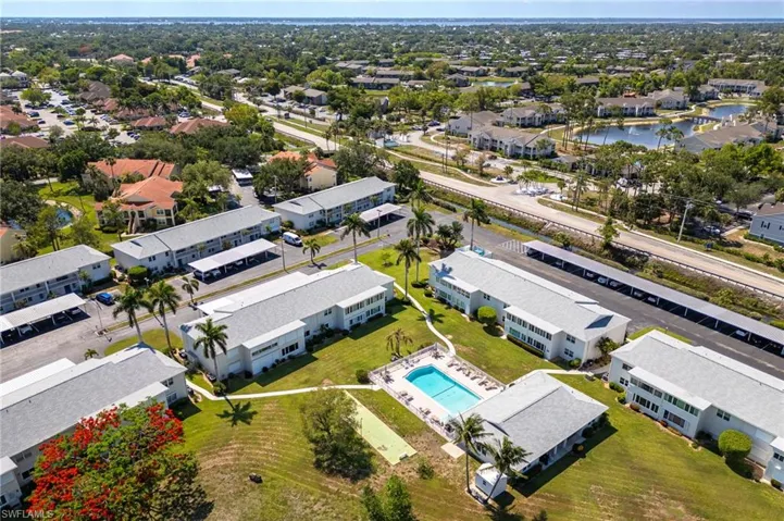 Aerial perspective showcasing multiple residential buildings with a central swimming pool and surrounding green spaces