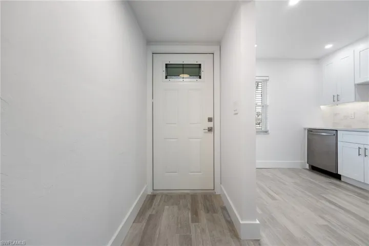 Entryway featuring a paneled door with an upper window, wood-finish flooring, and white baseboards