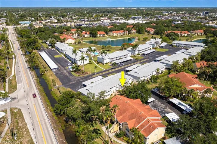 Aerial view of a residential complex featuring multiple buildings with diverse roofing, extensive parking areas, and mature landscaping