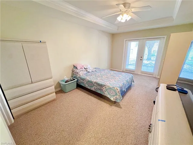 Bedroom with ornamental molding, carpet floors, access to exterior, a raised ceiling, and french doors
