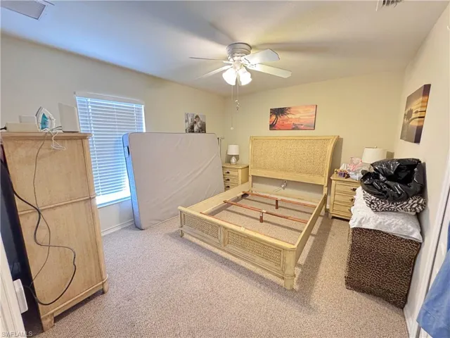 Carpeted bedroom with baseboards, a ceiling fan, and visible vents