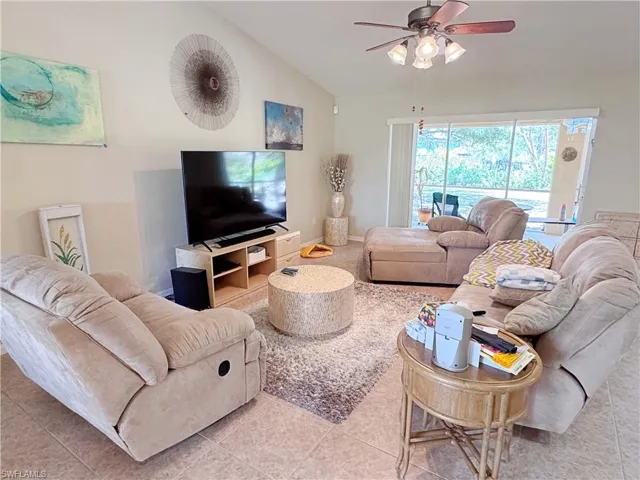 Living area featuring ceiling fan, vaulted ceiling, and light tile patterned flooring