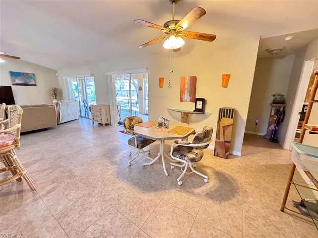 Dining space featuring a ceiling fan, tile patterned flooring, and lofted ceiling