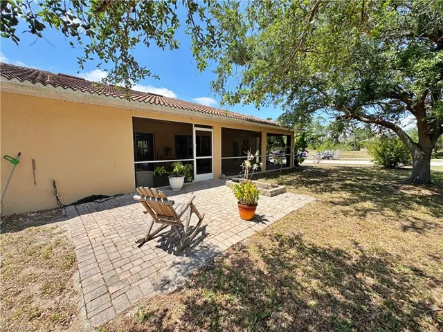 Back of house with a tiled roof, a sunroom, a yard, stucco siding, and a patio area