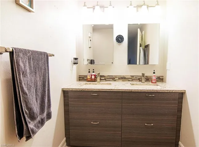 Bathroom featuring double vanity and backsplash