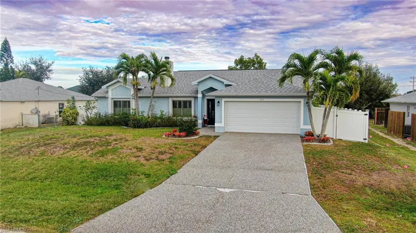 Ranch-style home with driveway, roof with shingles, stucco siding, an attached garage, and a gate