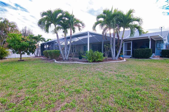 Rear view of property with glass enclosure, a sunroom, and a yard