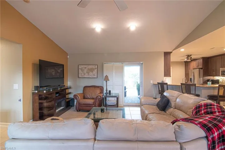 Living room featuring a ceiling fan, light tile patterned flooring, and vaulted ceiling