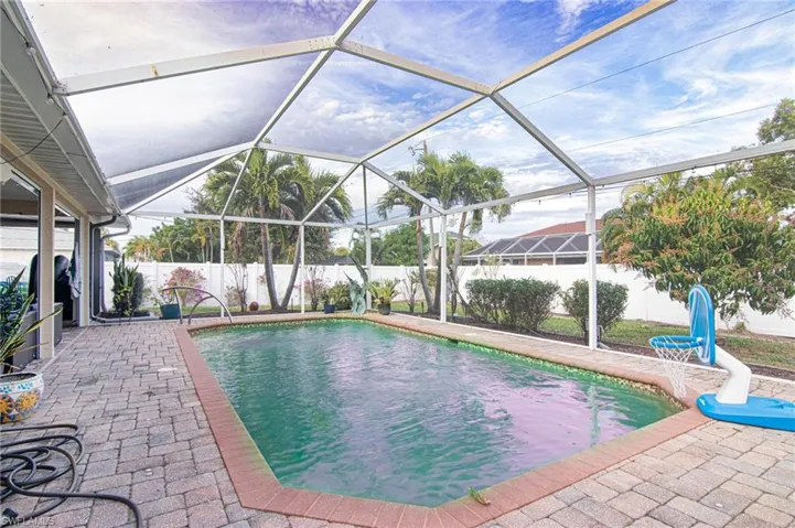 View of pool featuring a water slide, glass enclosure, a fenced backyard, a patio area, and a sunroom