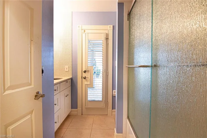 Bathroom with vanity, a shower with shower door, and light tile patterned floors