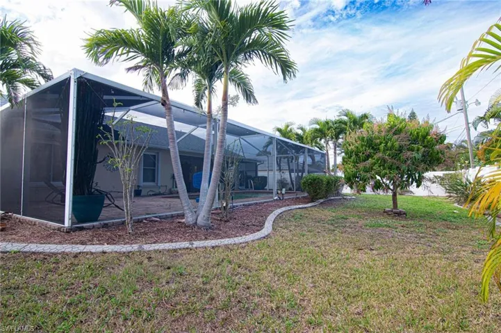 View of grassy yard with a lanai and a sunroom