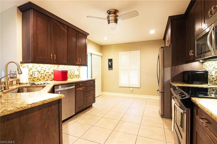 Kitchen featuring dark brown cabinets, light stone countertops, decorative backsplash, and recessed lighting