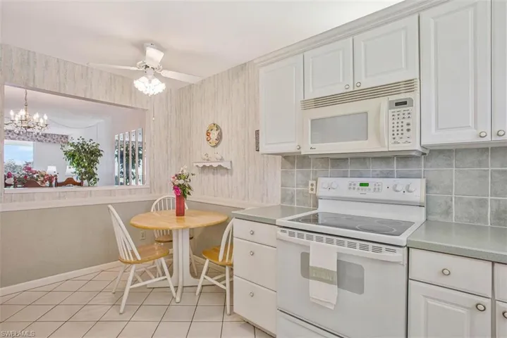 Eat in Kitchen featuring white appliances, light countertops, white cabinetry, and ceiling fan.  The little breakfast nook provides another eating area.