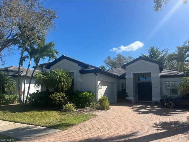 Ranch-style house with an attached garage, a tiled roof, stucco siding, decorative driveway, and a front yard