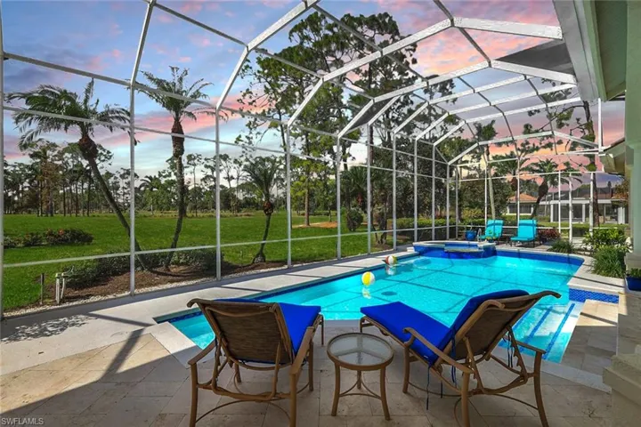 Pool at dusk with a lanai, an in ground hot tub, a yard, and a patio