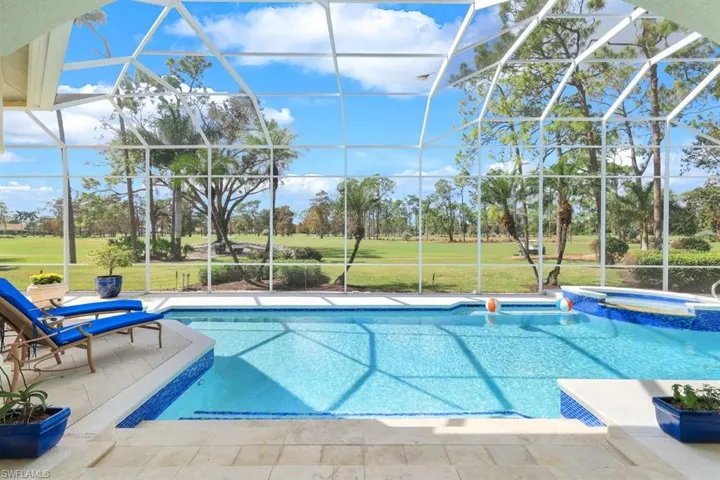 View of swimming pool with an in ground hot tub, a yard, a patio area, and a lanai