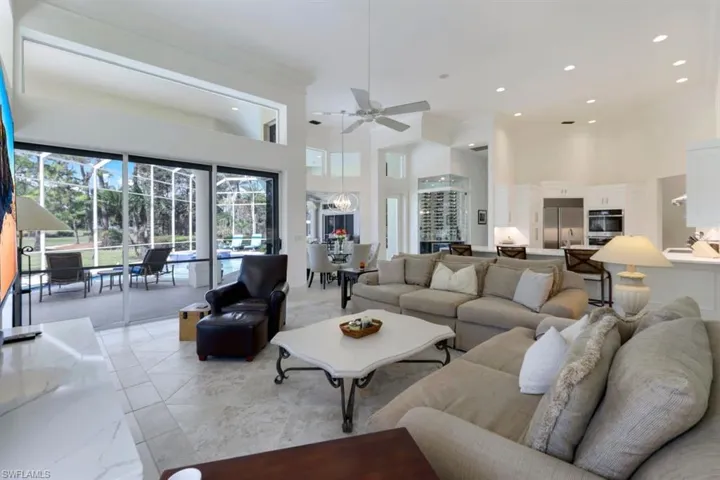 Living room featuring crown molding, a towering ceiling, and ceiling fan