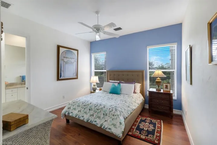 Bedroom with dark wood-type flooring, ceiling fan, and ensuite bathroom
