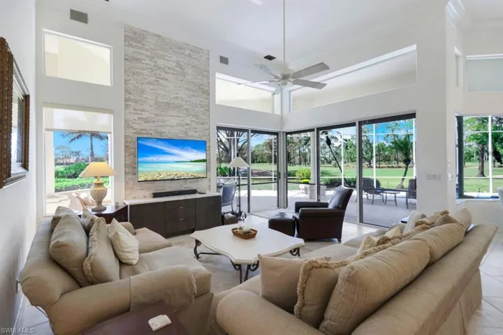 Tiled living room with ceiling fan, crown molding, and a high ceiling