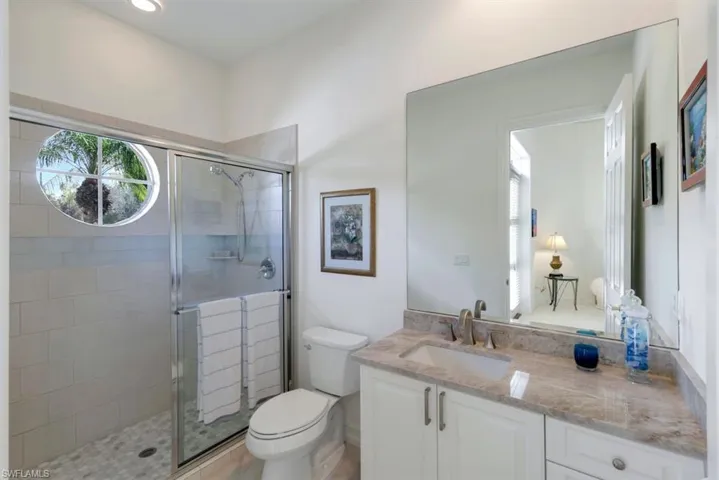 Bathroom featuring vanity, a shower with shower door, and toilet