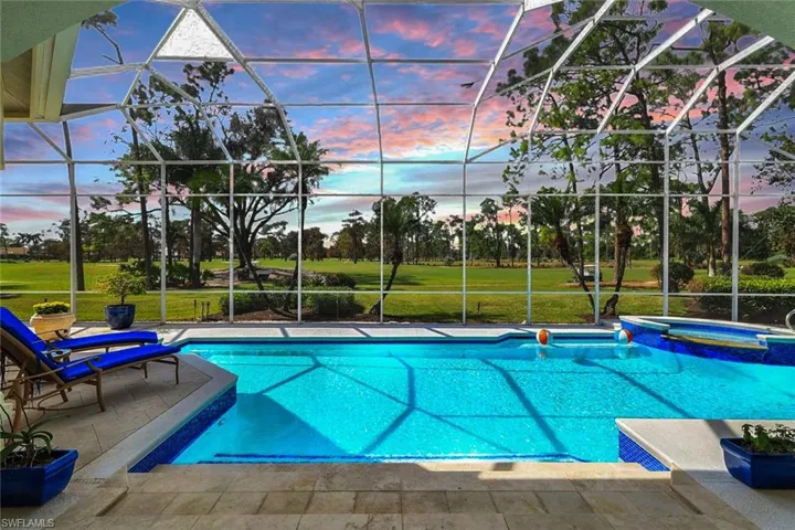 Pool at dusk with a yard, a patio, glass enclosure, and an in ground hot tub