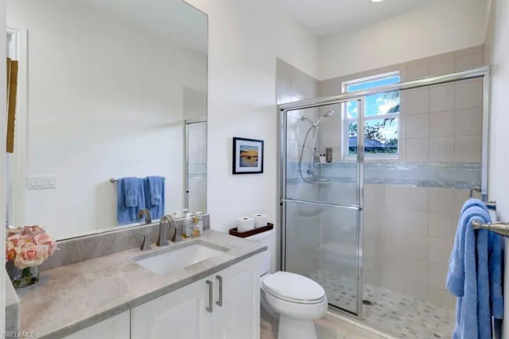 Bathroom with vanity, an enclosed shower, toilet, and tile patterned floors