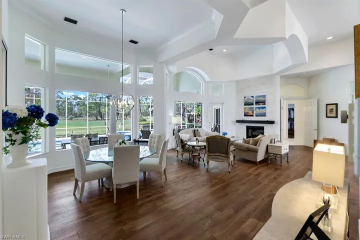 Dining space featuring a chandelier, a fireplace, a towering ceiling, and dark hardwood / wood-style flooring