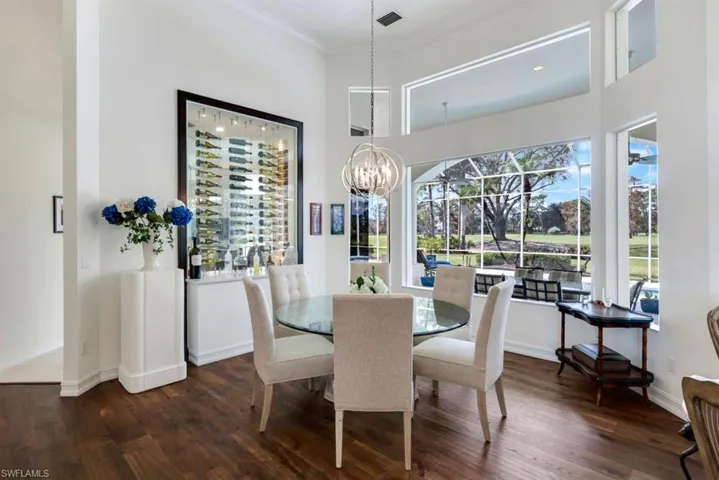 Dining space featuring an inviting chandelier, crown molding, a healthy amount of sunlight, and dark hardwood / wood-style flooring
