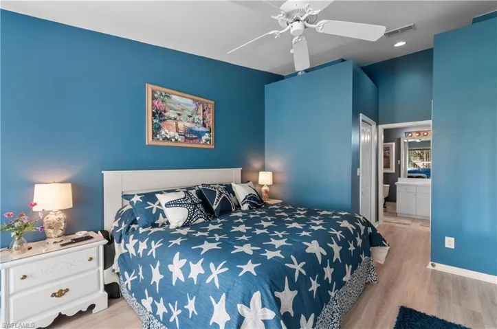 Bedroom featuring ceiling fan, light wood-type flooring, and ensuite bath