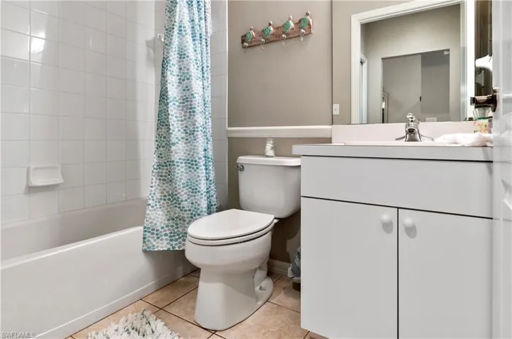 Full bathroom featuring toilet, tile patterned floors, shower / bathtub combination with curtain, and vanity