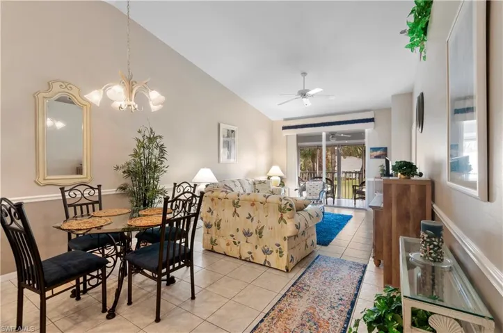 Tiled dining room featuring lofted ceiling and ceiling fan with notable chandelier