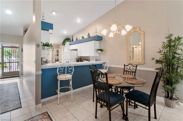 Tiled dining area featuring vaulted ceiling and an inviting chandelier