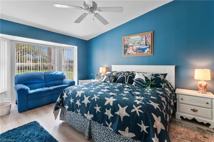Bedroom with ceiling fan, vaulted ceiling, and light wood-type flooring