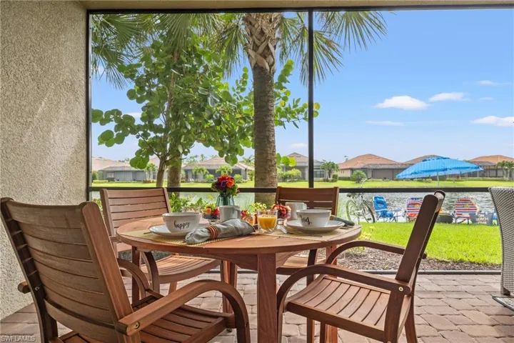 Screened patio featuring a paver stone surface, stucco exterior, and mature tropical landscaping