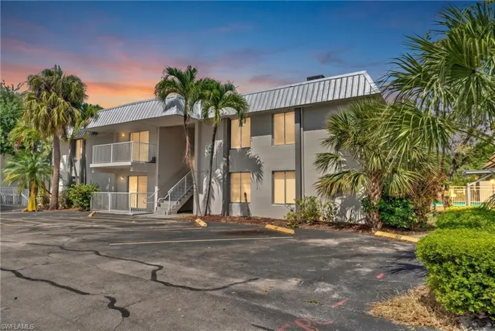 Multi-story residential building with a corrugated metal roof and a light gray exterior