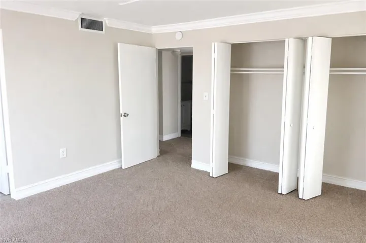 Plush neutral carpeting extends throughout the room, complemented by neutral wall paint and white crown molding