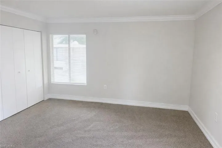 Neutral tone walls featuring crown molding and baseboards