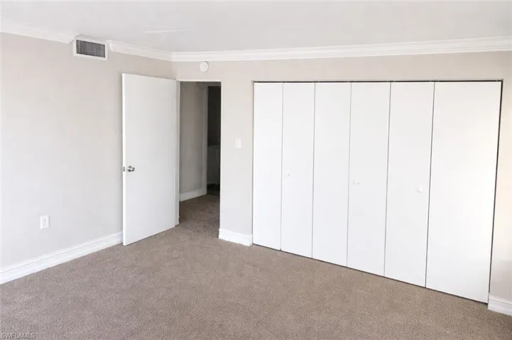 Neutral-toned carpeting extends throughout this room, complemented by white baseboards and crown molding