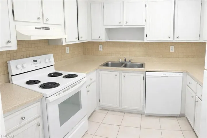 Full kitchen featuring white cabinetry, a dual basin stainless steel sink, a range with an overhead exhaust hood, a white dishwasher, and light-toned countertops with a tiled backsplash