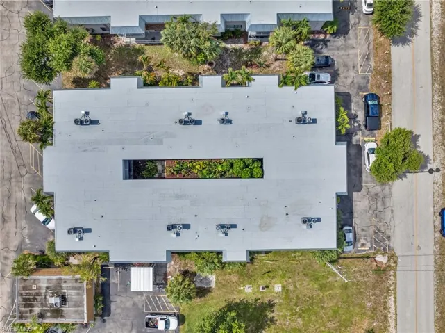 Commercial building featuring a flat roof with an open-air courtyard, multiple rooftop HVAC units, and surrounding paved parking areas