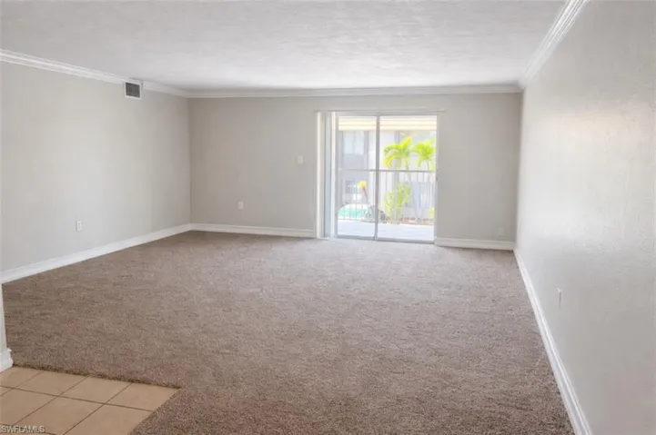 Expansive living area featuring plush carpet flooring and a sliding glass door