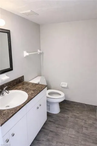 Bathroom featuring a white vanity with a dark speckled countertop, an oval undermount sink, and chrome fixtures