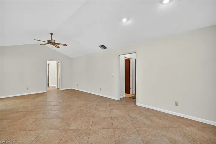 Empty room featuring vaulted ceiling, ceiling fan, and light tile patterned floors