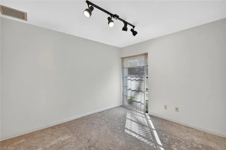 Unfurnished room with baseboards and rail lighting