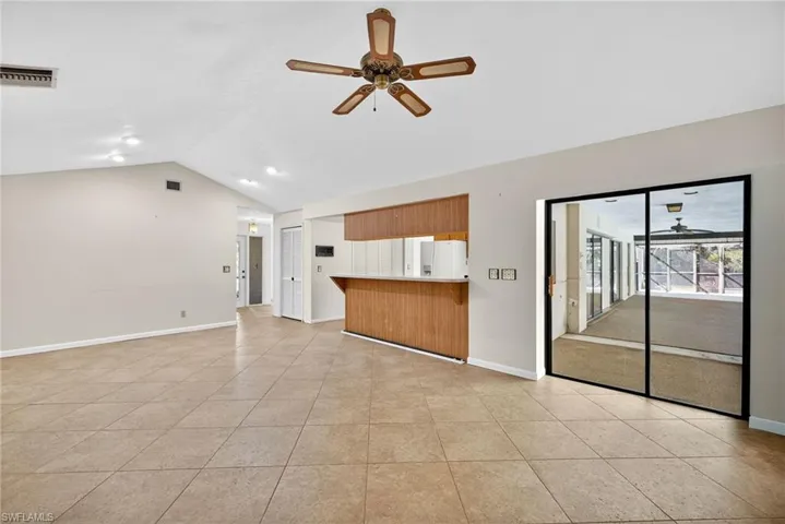 Unfurnished living room featuring a ceiling fan, lofted ceiling, and light tile patterned flooring