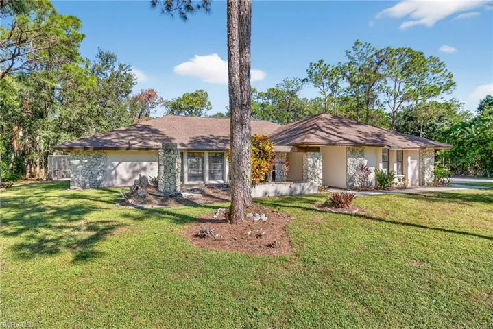 View of front of home with a front yard, stone siding, and stucco siding