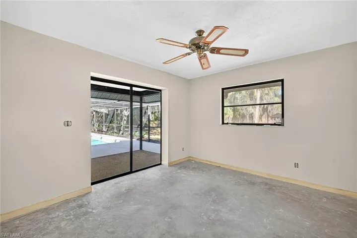 Spare room featuring unfinished concrete flooring, a sunroom, and a ceiling fan